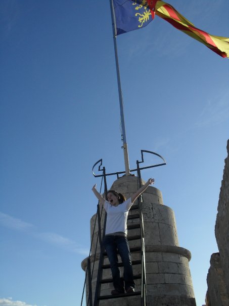 Madeline Parente in Spain on top of the old gate in to the city of Valenica. Spanish flag waving behind.